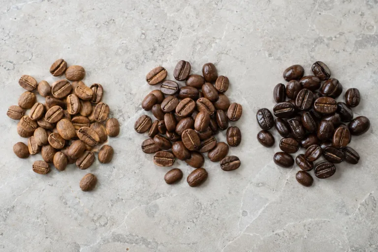 Three small groups of roasted coffee beans ranging from light brown to dark brown